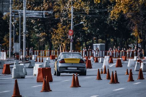 Yellow grey car driving through traffic cones in city · Free Stock Photo