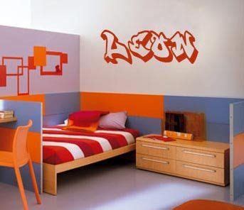 an orange and blue bedroom with a bed, desk, chair and wall decal