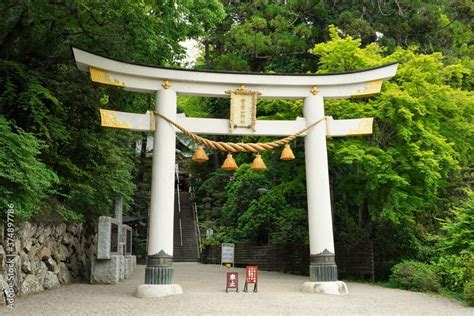 Shrine white and gold big gate called "Torii" . Japanese text on gate ...