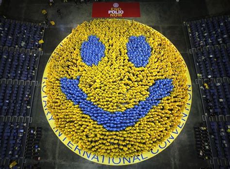 a smiley face made out of flowers in the middle of an arena with people standing around it