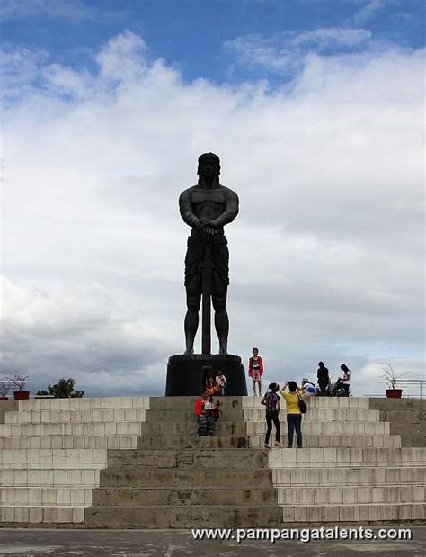 Lapu-lapu monument side view with clouds and flowers deside the Department of Tourism