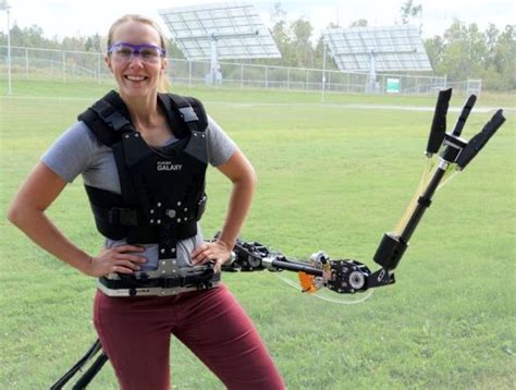 a woman standing in front of a field with a camera attached to her ...