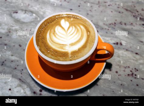 Caffe latte with latte art served in an orange cup and saucer. Seattle Stock Photo - Alamy