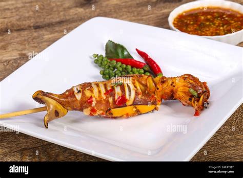 Grilled squid skewer with sauce and hebs Stock Photo - Alamy