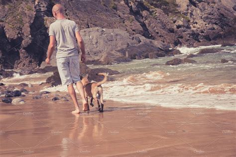 Man walking with a dog on the beach | People Images ~ Creative Market