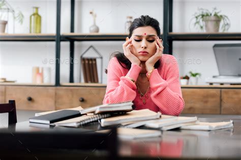 sad indian student with bindi studying at home with books Stock Photo by LightFieldStudios