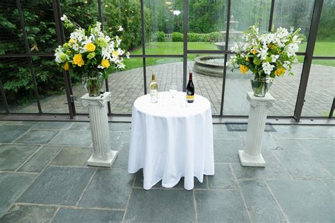 two vases with flowers and wine bottles on a table in front of a glass wall