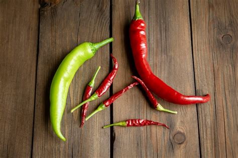 Premium Photo | Green and red chili on a wooden table different varieties of hot peppers on a ...