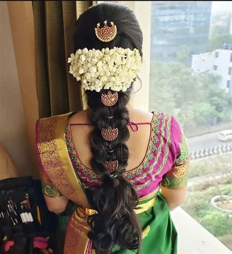 a woman with long hair wearing a green saree and flowers in her hair ...