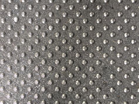 Diagonal pattern of silver metal bolts in pavement | Free Textures