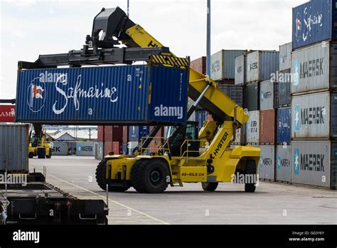 A heavy lifting machine unloading and loading cargo and shipping containers onto goods trains in ...