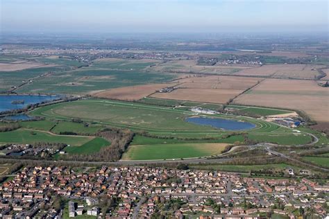 an aerial view of a small town with lots of green fields and water in ...