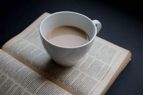 Top View Close Up Photo of Cup of Coffee standing on open Book on Black ...