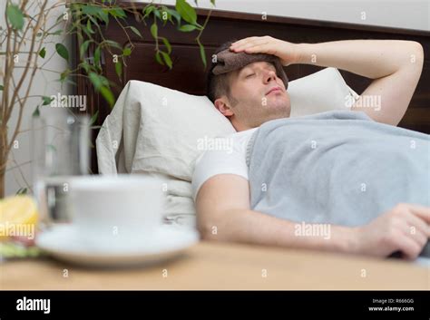 Sick man with fever lying in the bed Stock Photo - Alamy