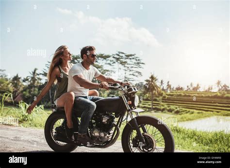 Side view shot of young couple on motorbike. Man riding on a motorcycle with girlfriend on ...