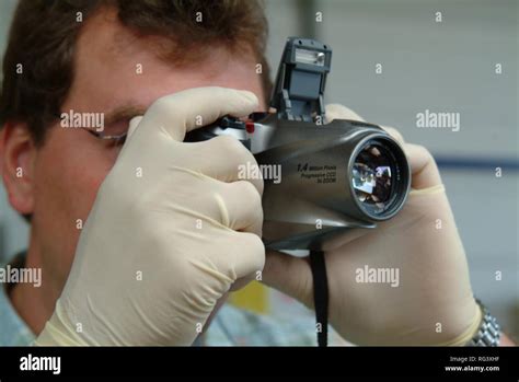 DEU, Germany, NRW: Forensic police investigator takes photos at a crime scene, with a digital ...