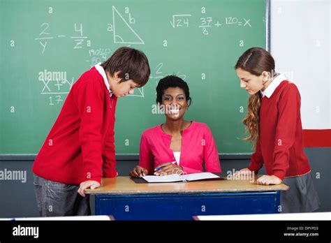 Teacher With Students At Desk Stock Photo - Alamy