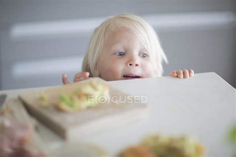 Curiosity boy peeking over kitchen counter — childhood, Mischief - Stock Photo | #167858778