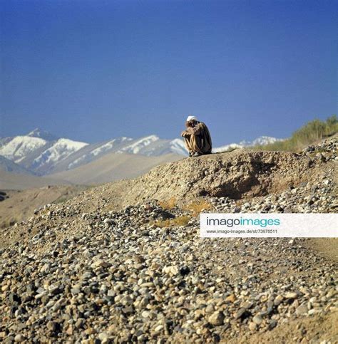 Afghanistan, Bamian Valley. A shepherd waits in the rocky foothills in the Bamian Valley, a World