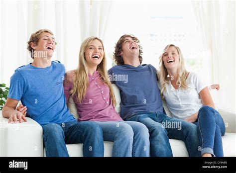 Laughing friends sit on the couch together Stock Photo - Alamy