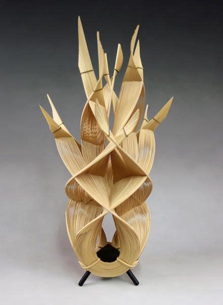 a sculpture made out of folded paper on top of a black stand with an object in it's center