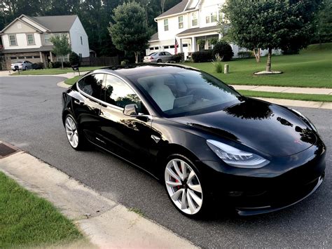 a black tesla parked in front of a house