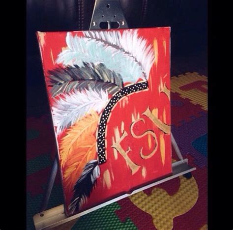 an easel with a painting on it that has feathers painted on the front ...