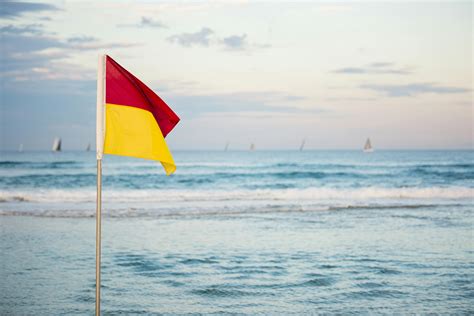 Red And Yellow Flag Standing Near Beach · Free Stock Photo