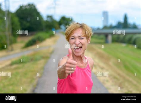 Enthusiastic woman giving a thumbs up gesture with a beaming gleeful smile as she celebrates a ...