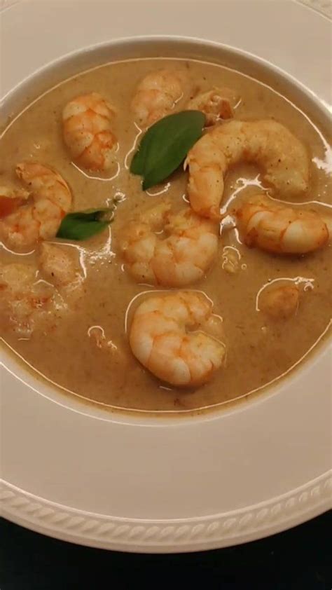 a white plate topped with soup and shrimp