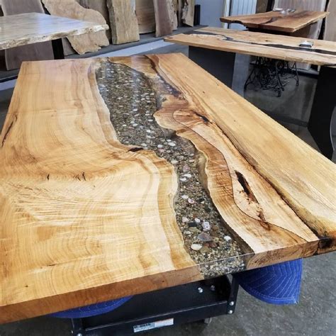 a table made out of wood and rocks with water running down the center, surrounded by other tables