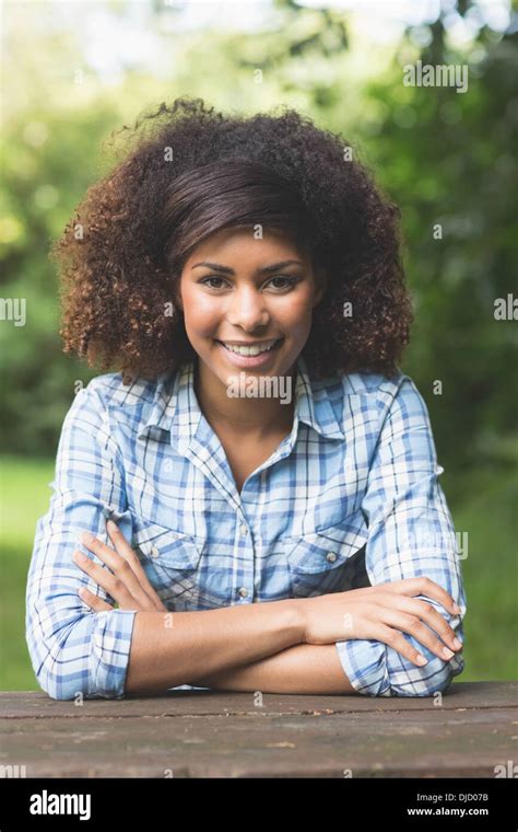 Gorgeous smiling brunette sitting at picnic table Stock Photo - Alamy