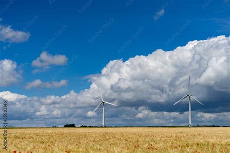 Photograph of two wind turbines on a blue sky with intermittent clouds ...