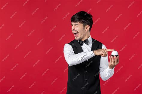 Premium Photo | Top view of funny guy waiter in a uniform with bow tie holding pushing ring bell.