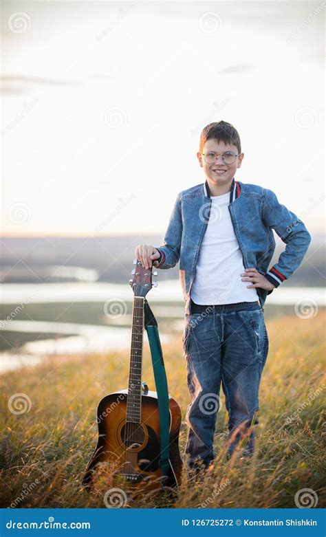 Young Teen Boy Holding Acoustic Guitar at Summer Field on Sunset and ...