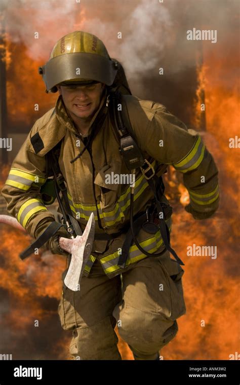 Firefighter running through fire holding an axe Stock Photo - Alamy