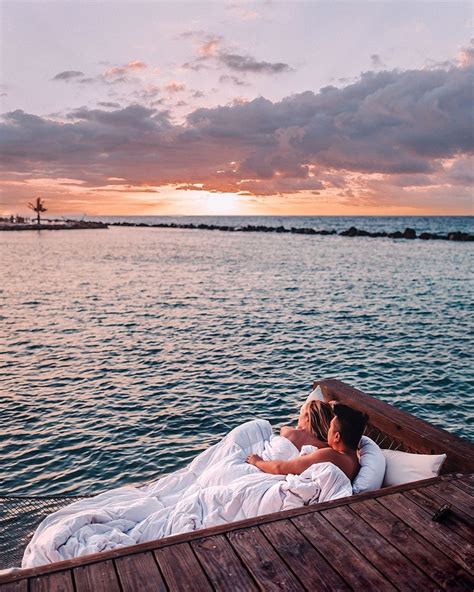 two people are laying on a boat in the water at sunset, with one person kissing the other