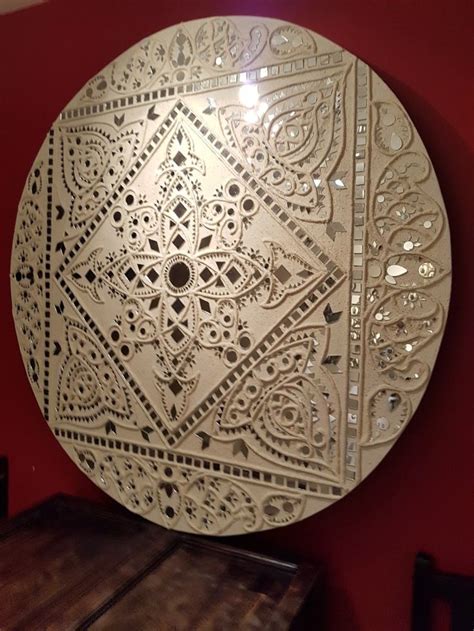 a decorative white plate sitting on top of a wooden table next to a red wall