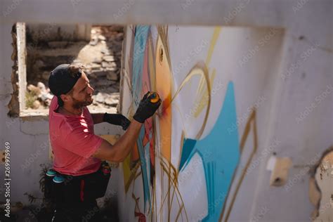 Graffiti artist spray painting on weathered wall room Stock Photo | Adobe Stock