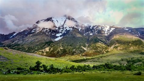 Landscape photography of green fields and snow covered mountain range ...