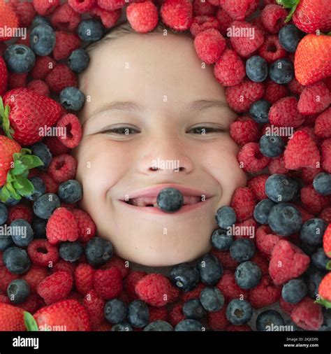 Berries child face close up. Top view photo of child face with berri. Berry set near kids face ...