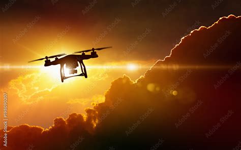 Silhouette of flying drone in glowing red sunset sky Stock Photo | Adobe Stock