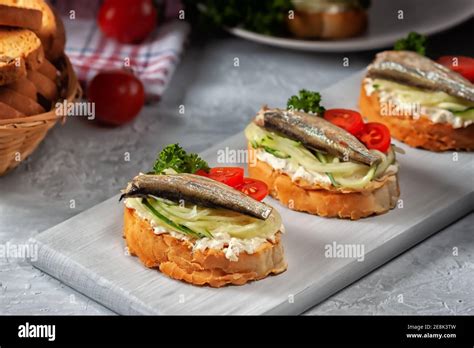 Smoked sprat sandwich - fish, fresh cucumber and tomato. Sprat sandwiches on toasted slices of ...