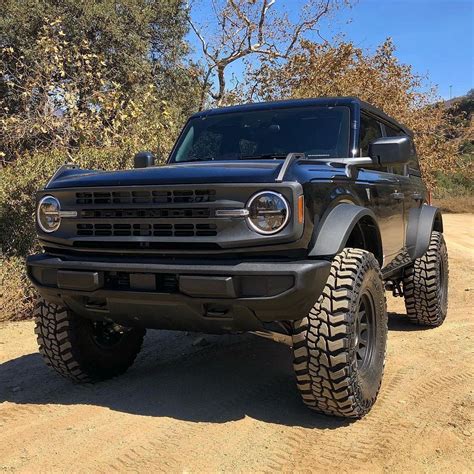 a black truck parked on top of a dirt road