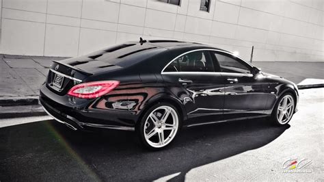 a black car parked on the street in front of a building with white rims