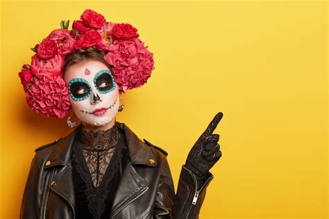 Free Photo | Serious young lady wears dead mask skull makeup, flower wreath, points on free ...