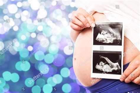 Pregnant woman showing ultrasound scans against glowing background ...