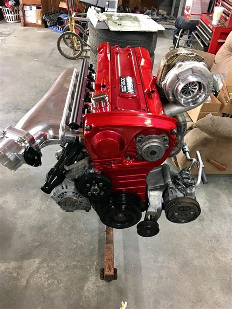 a red engine sitting on top of a metal stand in a garage next to boxes