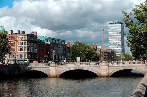 a bridge over a body of water with tall buildings in the background on a cloudy day