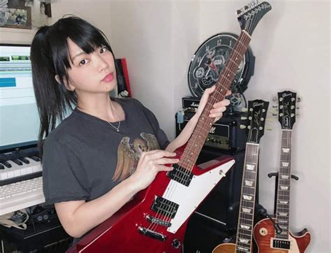 a woman is holding an electric guitar in front of a keyboard and other musical instruments